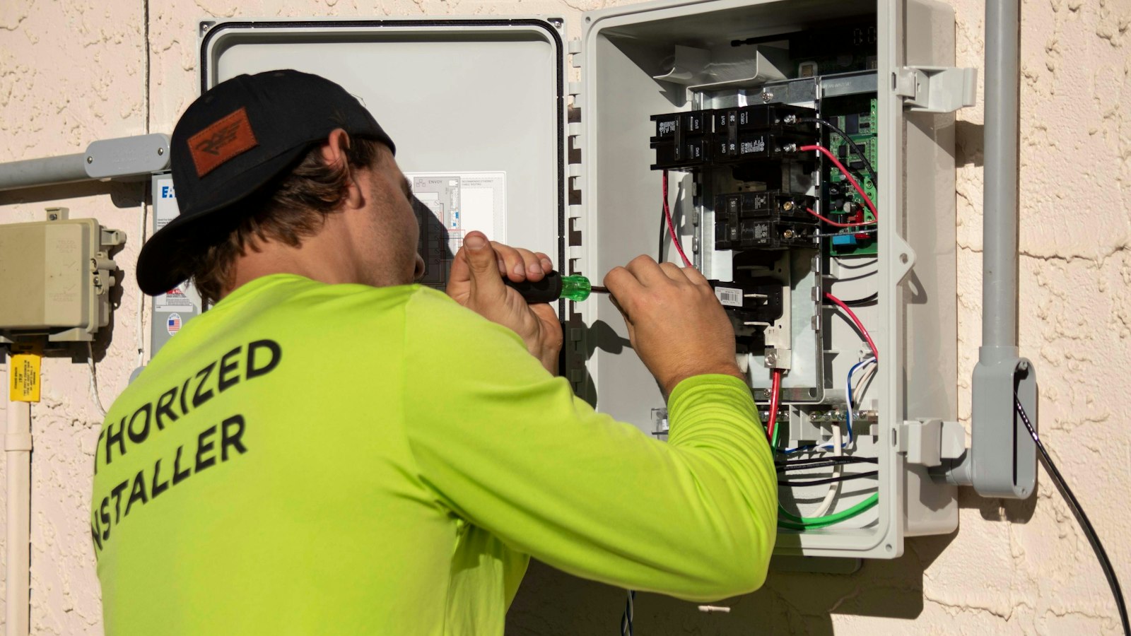 Eletricista a reparar uma caixa elétrica com chave de fendas