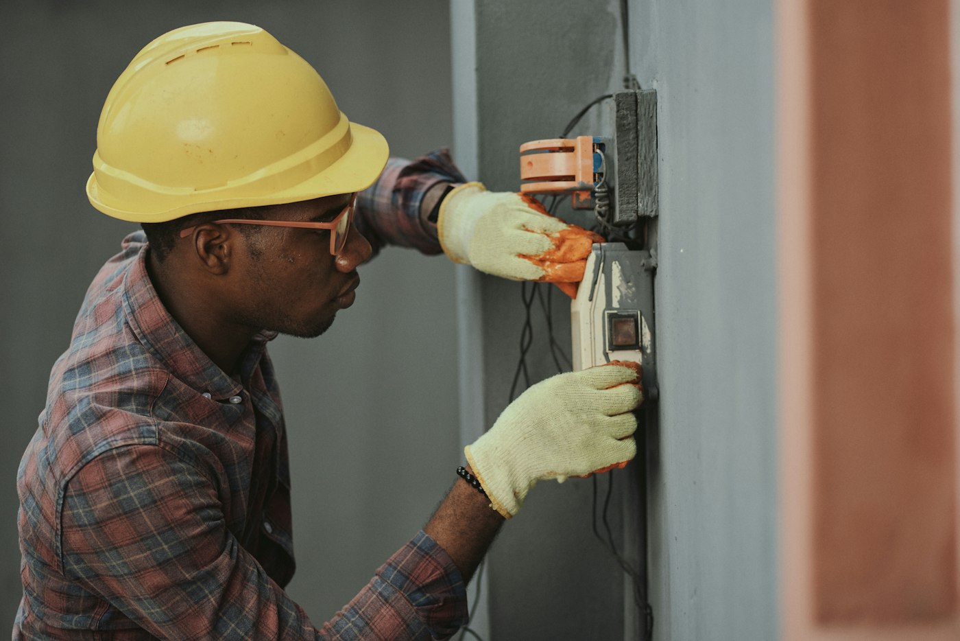 Eletricista com capacete e luvas a trabalhar numa instalação elétrica